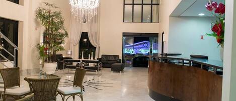 A spacious lobby with a reception desk, seating area, and a large chandelier.