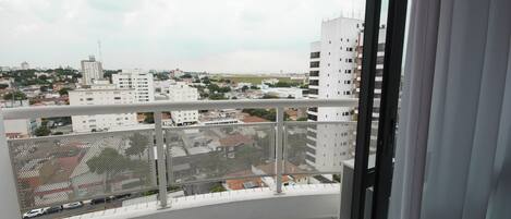 Uma varanda com vista para a paisagem urbana, incluindo edifícios e uma estrada.