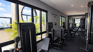 A gym with exercise equipment, large windows, and a view of the city.