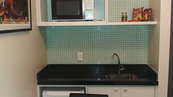 Cocina compacta con microondas, lavavajillas y una pequeña zona de comedor con mesa y sillas.