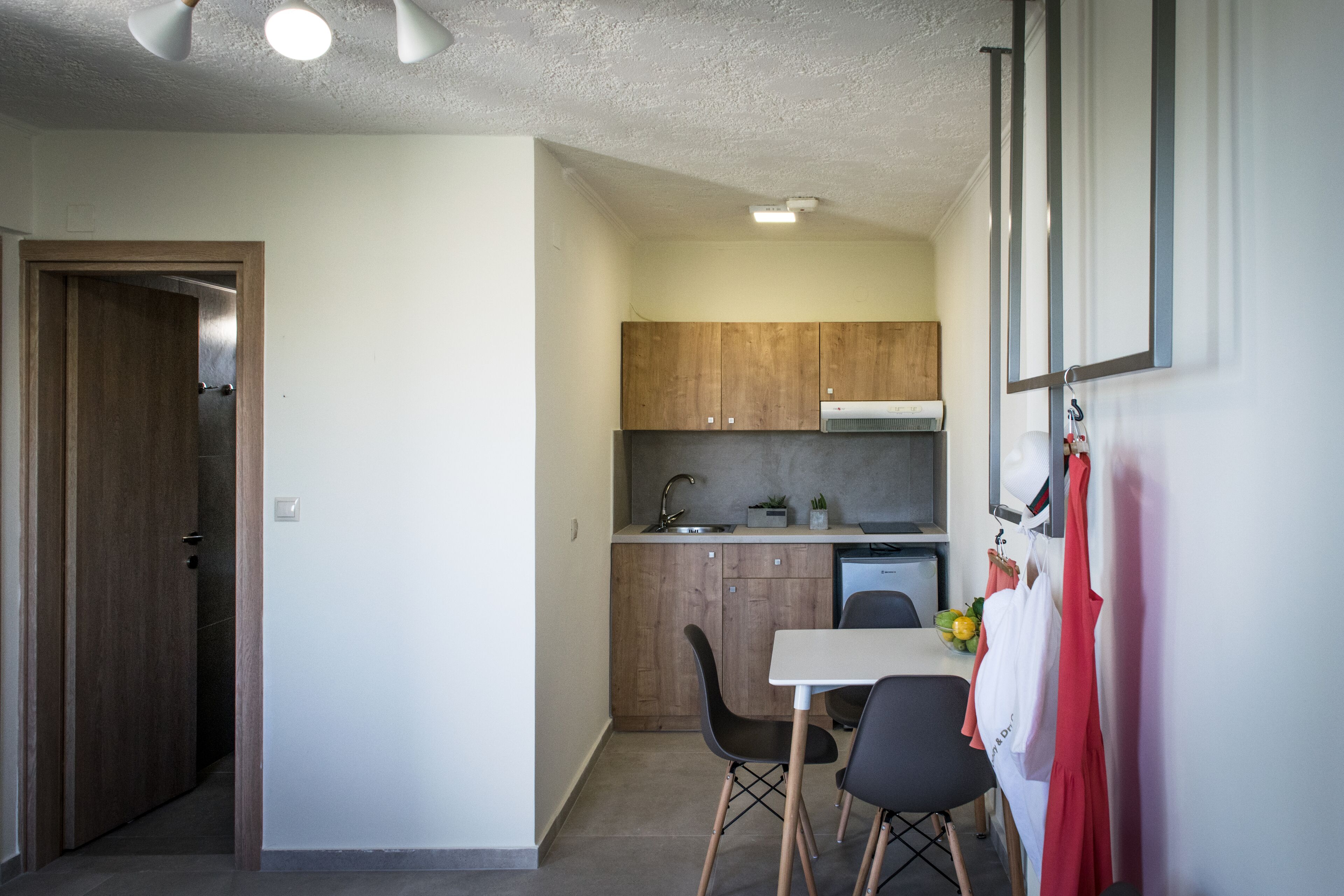 A compact kitchen with wooden cabinets, a white countertop, and a small dining area with two chairs.