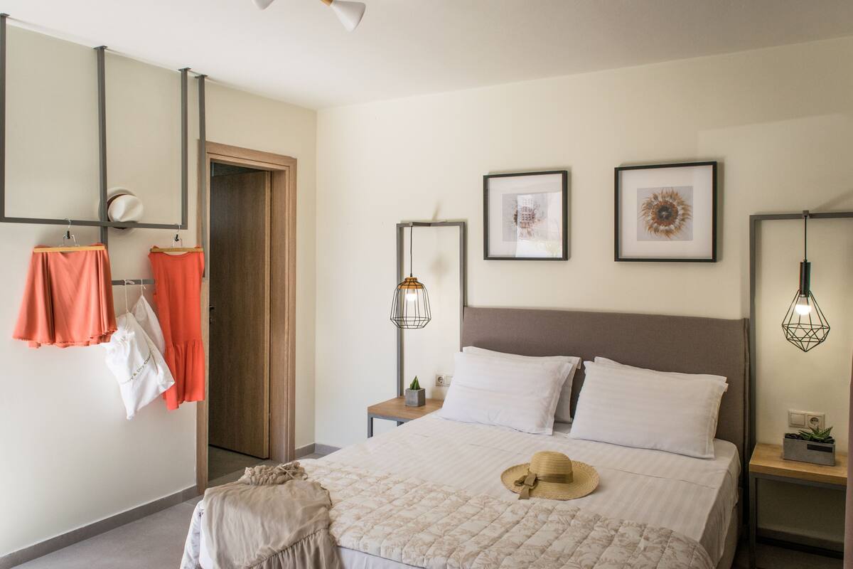 A neatly arranged bedroom with a bed, bedside tables, a hanging light fixture, and a door.