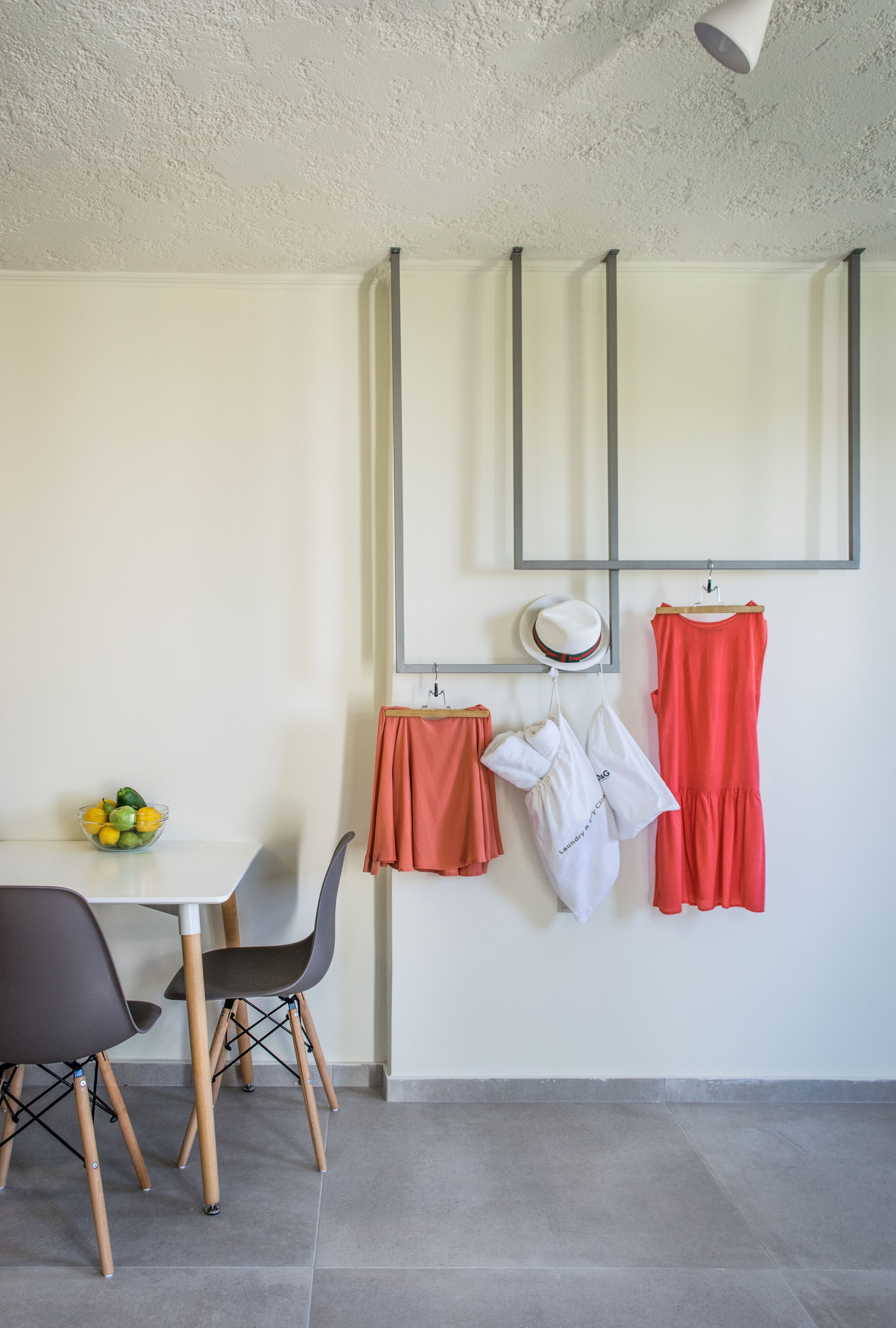 Un comedor con una mesa y sillas blancas, un frutero y un espejo colgado en la pared.