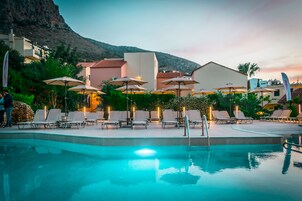 Una piscina al aire libre, sombrillas, sillones reclinables de piscina