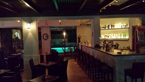 A dimly lit bar area with a pool table and a bar counter displaying various bottles. - Maria Lambis Apartments (Hersonissos)