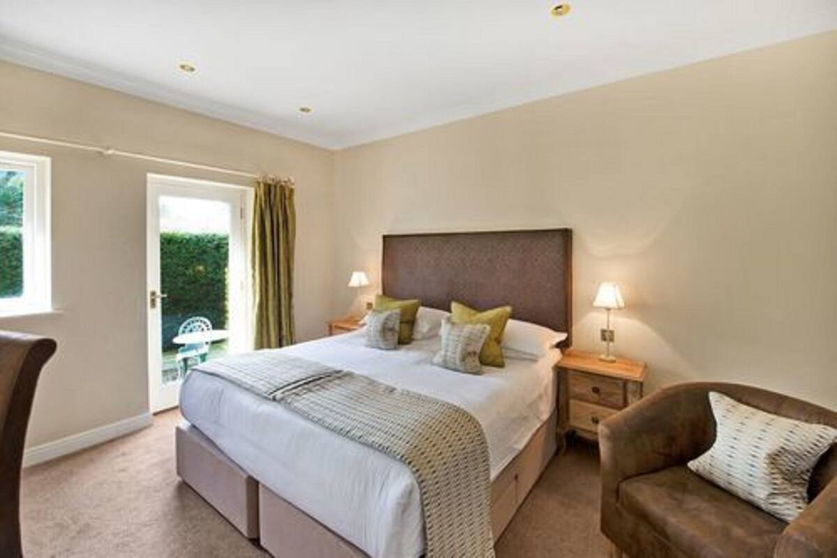 A bedroom with a large bed, bedside tables, a chair, and a view of greenery outside.