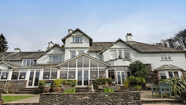 A large, white, two-story house with a conservatory, stone steps, and a garden with benches. - The Ryebeck Country House & Restaurant (Windermere)