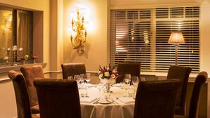 A dining room with a round table set for four, surrounded by brown upholstered chairs.