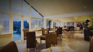 A spacious dining area with large windows, several tables set for dining, and chairs arranged around them. - The Ryebeck Country House & Restaurant (Windermere)
