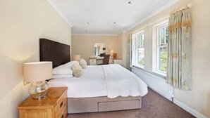 A bedroom with a bed, bedside table, lamp, and a window with curtains.