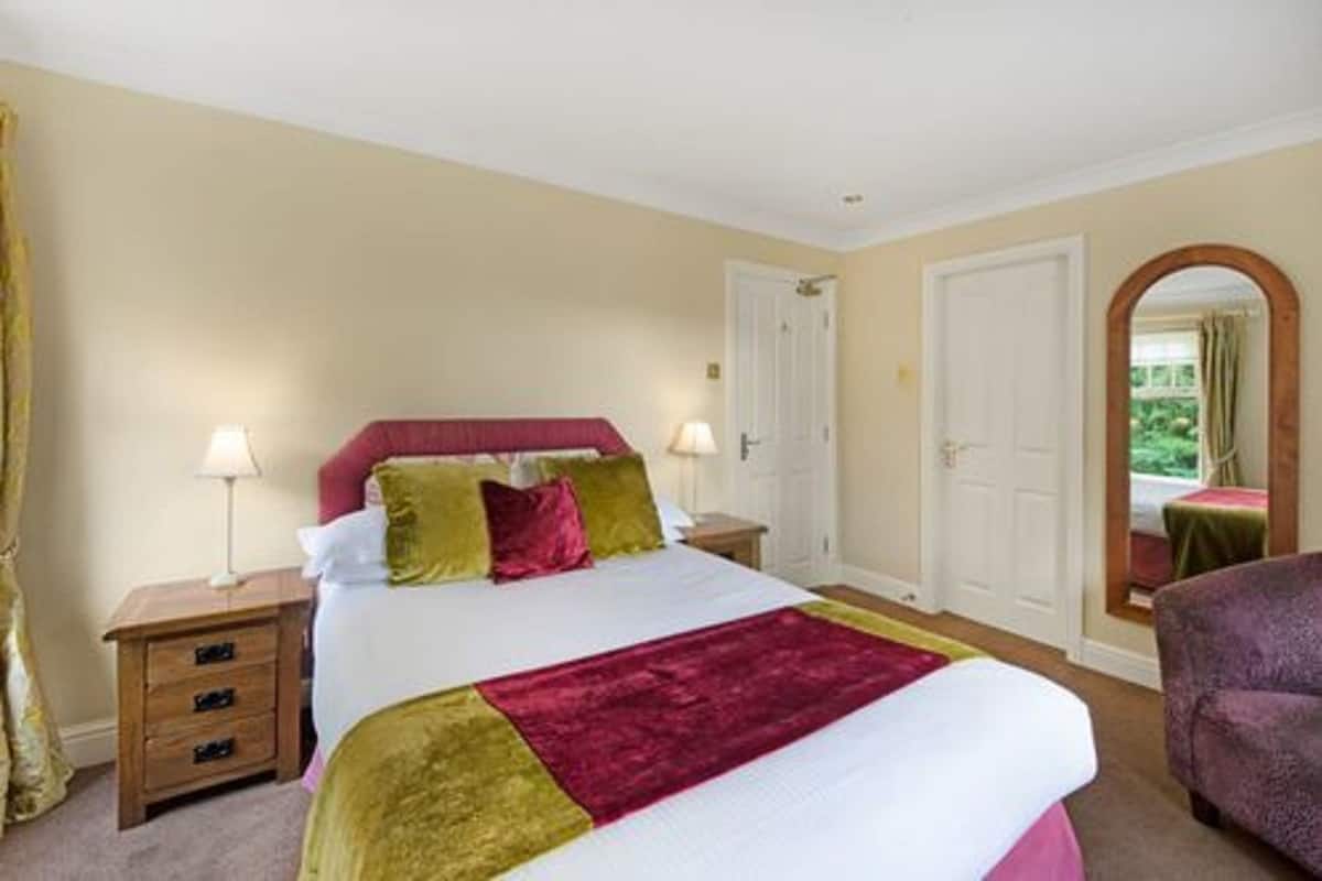 A bedroom with a bed, nightstands, a mirror, and a door.