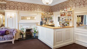 A bar area with a white counter, shelves of bottles, and a chandelier. - The Ryebeck Country House & Restaurant (Windermere)