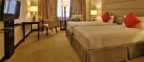 A hotel room with two beds, a TV, a desk, and a chair.