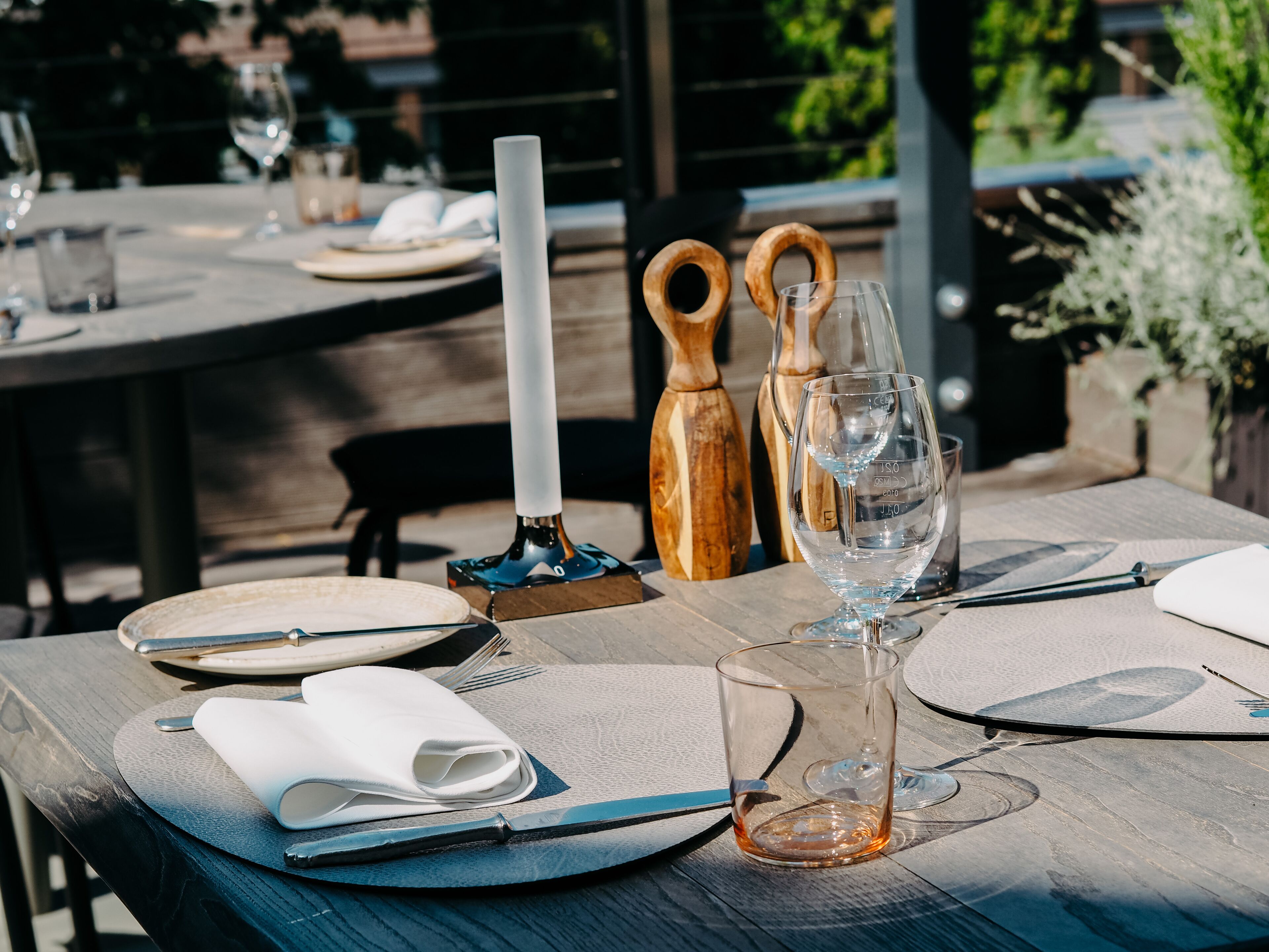 Ein Tisch für ein Essen im Freien mit Tellern, Besteck und Gläsern.