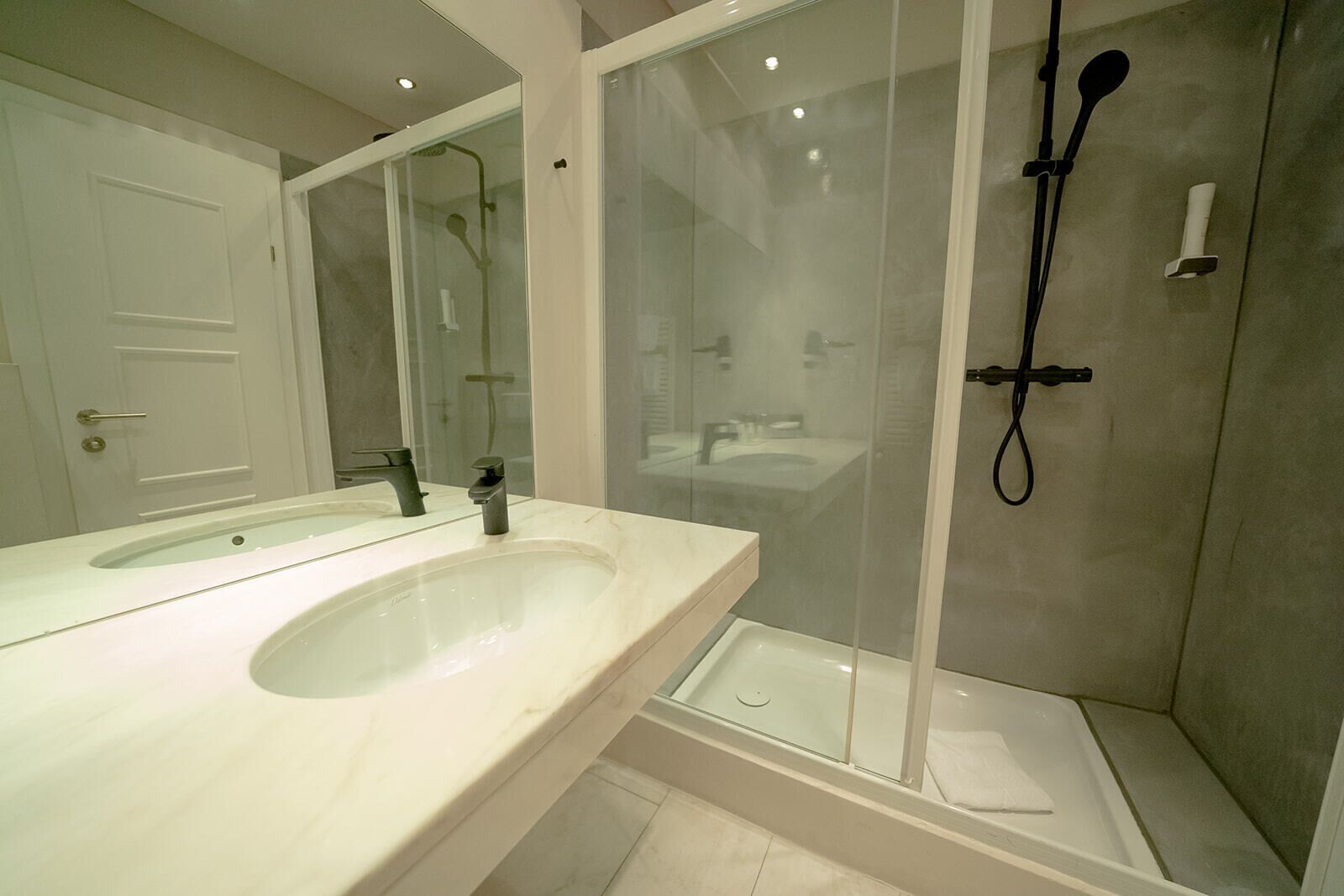 A modern bathroom with a large sink, a mirror, and a glass-enclosed shower area.