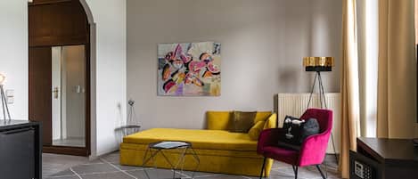 A modern living room with a yellow sofa, a red chair, a black coffee table, and a floor lamp.