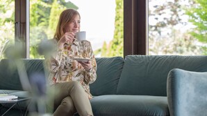 A person sitting on a sofa with a window behind them.
