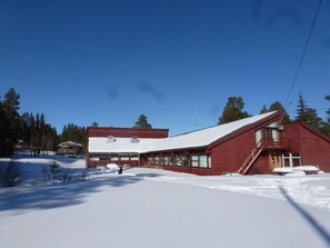 A red building with a sloped roof, large windows, and a staircase leading to a porch. - Gjesteheim Havdal - Hostel (Rennebu)