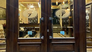 Entrada de hotel con puertas dobles, un cartel que dice "Prince Hotel" y el reflejo del interior del hotel.