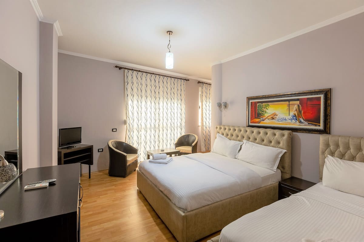 Una habitación de hotel con una cama grande, televisión, escritorio con computadora y una silla.