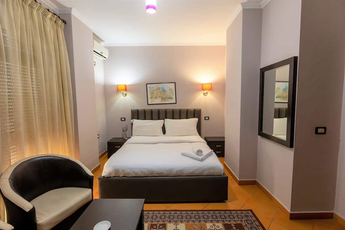 Una habitación de hotel con una cama, una silla, un escritorio y una alfombra.