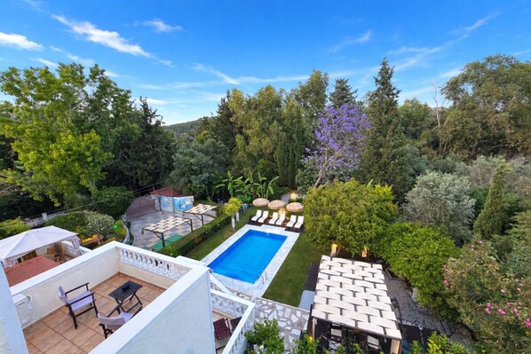 A rooftop pool with lounge chairs, a barbecue area, and a view of the surrounding greenery. - Villa Small Paradise (Rhodes)