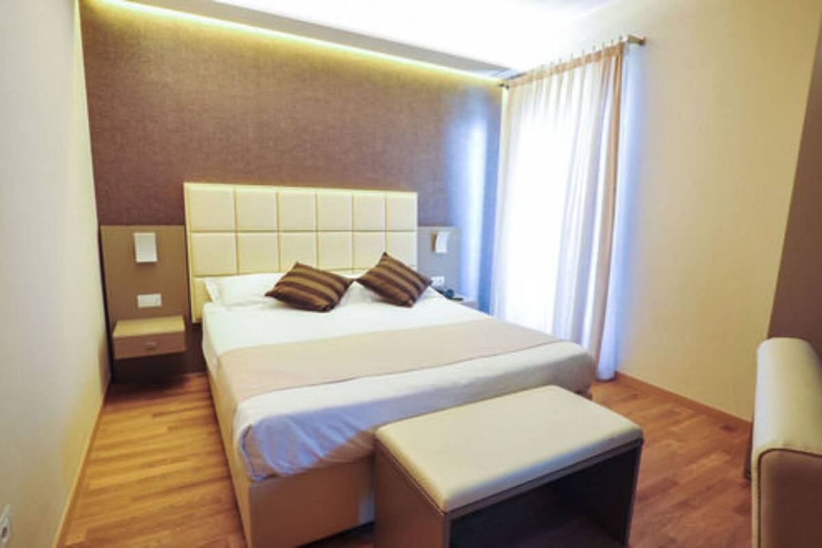 A hotel room with a large bed, a bedside table, a chair, and a window with curtains.