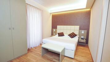 Un dormitorio moderno con una cama grande, un banco, un armario y una mesita de noche.