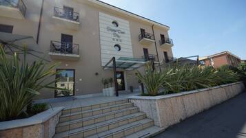 A hotel with a beige facade, multiple balconies, and a clear entrance.