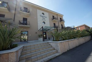 A hotel with a beige facade, multiple balconies, and a clear entrance.