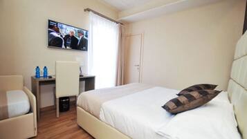 Una camera d'albergo con un letto, una scrivania, una sedia, una televisione e una porta.