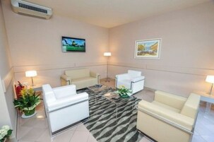 Una habitación de hotel moderna con un conjunto de sofá, una mesita de centro y dos lámparas de pared.