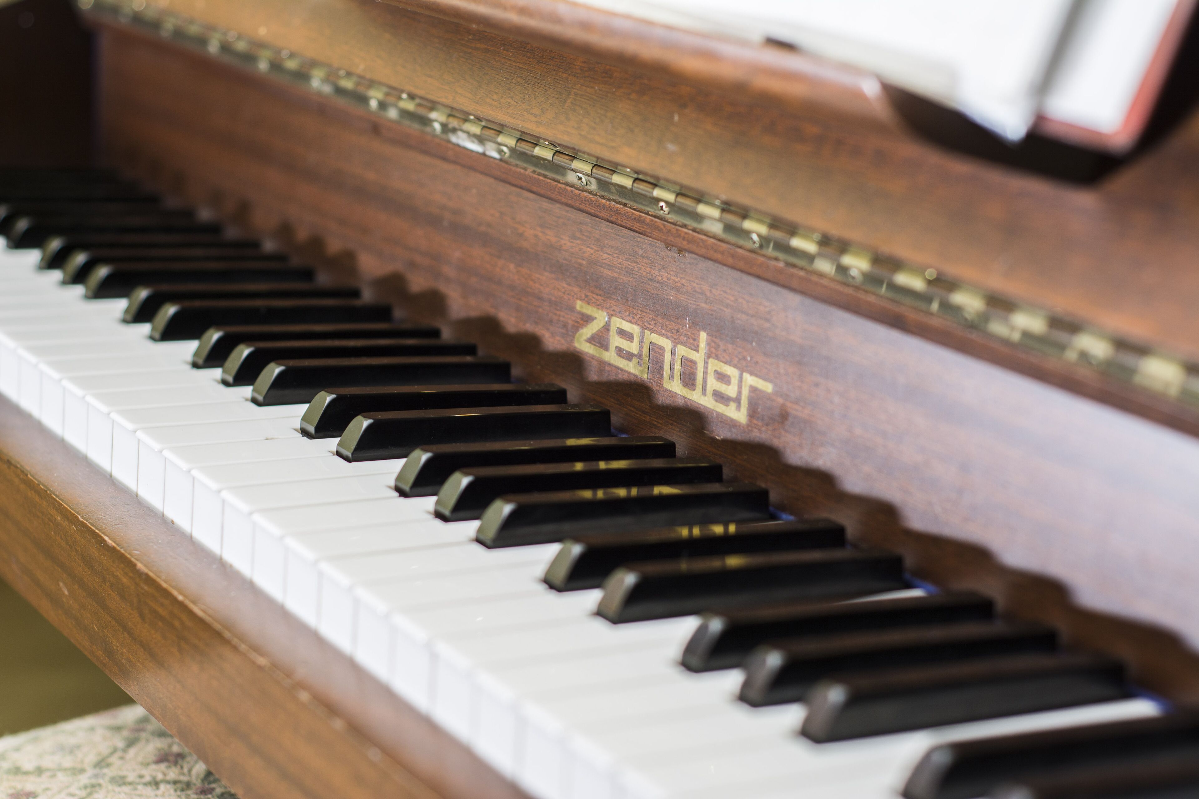 Une vue rapprochée d’un piano, sur lequel on peut voir le nom de la marque « Zender » sur le côté.
