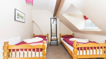 A room with two wooden beds, a mirror, and a window.