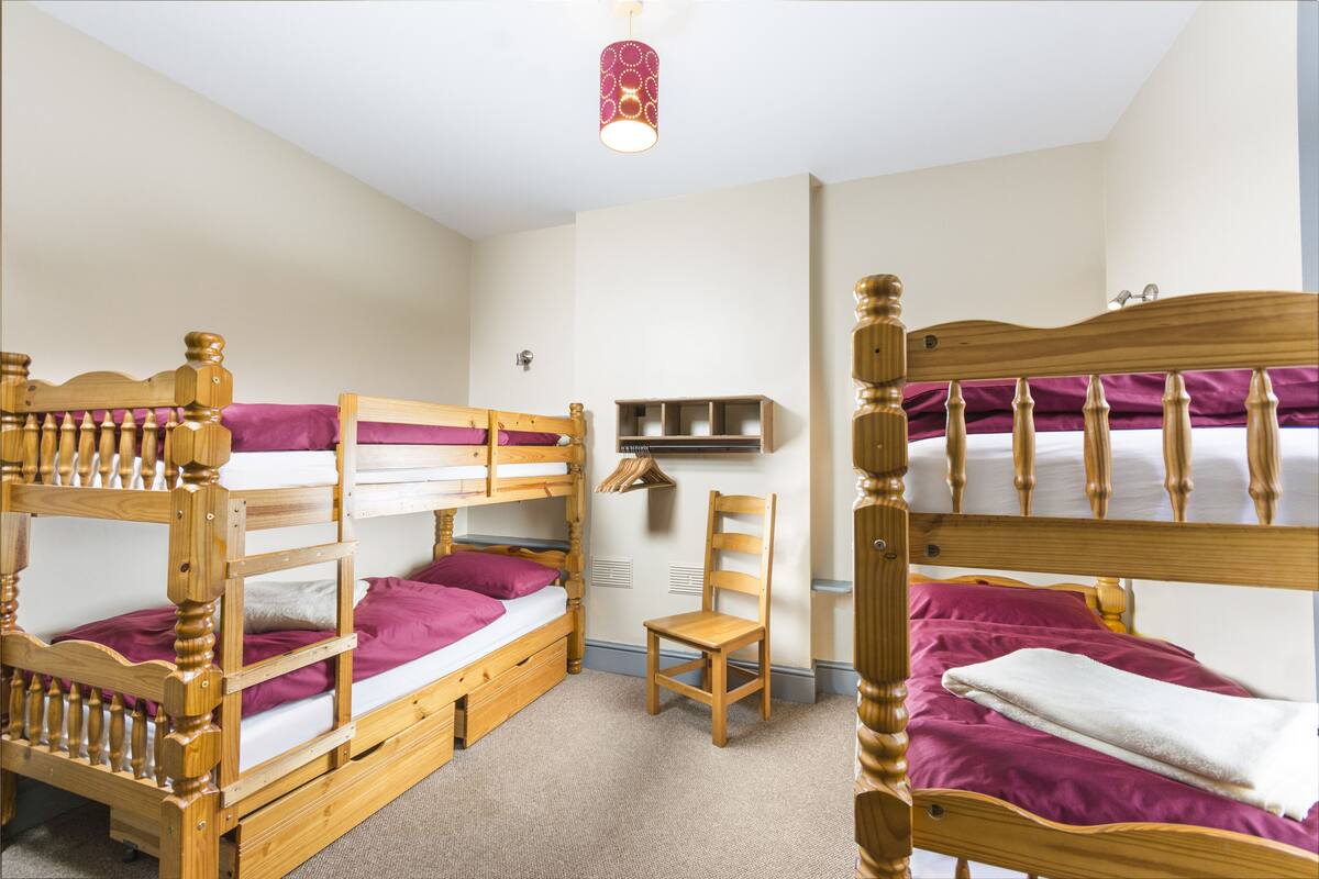 A bunk bed room with a wooden headboard, a chair, and a shelf.