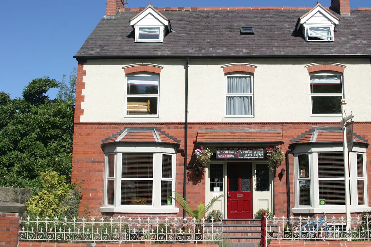 A two-story building with a red door, multiple windows, and a sign indicating family rooms.