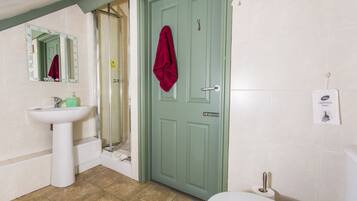 A bathroom with a sink, mirror, green door, and a towel hanging on the door.