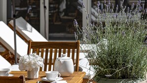 Una mesa de madera con tazas blancas, un calentador de agua y una planta de lavanda en maceta.