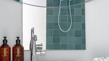 Een badkamer met een witte wastafel, een handdouche en twee flessen shampoo.