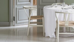 Un comedor con una mesa redonda dispuesta para dos personas, una silla blanca y una lámpara colgante.