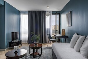 Una habitación de hotel moderna con una cama grande, un escritorio, una silla, un televisor y un jarrón con flores.