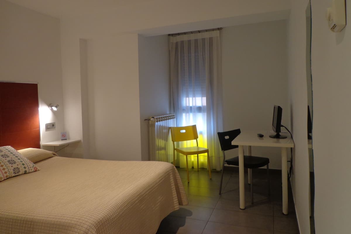 Una habitación de hotel con una cama, un escritorio y una silla.