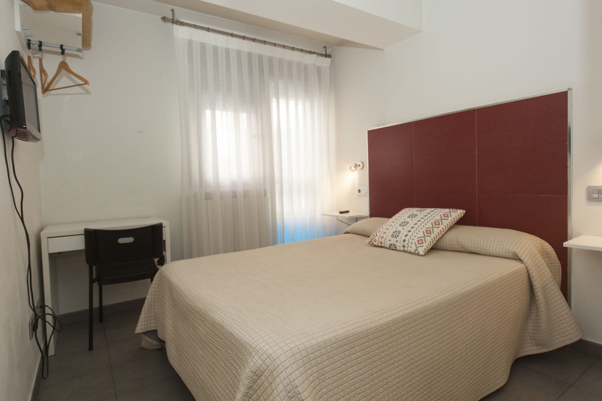 Un dormitorio con cama, escritorio y silla.