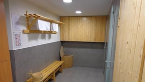 A small, enclosed bathroom with a wooden bench, a wooden shelf with towels, and a wooden cabinet. - Alda Soria Rooms (Soria)