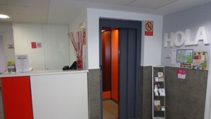 A reception area with a red and white counter, a 'NO USE' sign, and a 'HOLA' sign above a door. - Alda Soria Rooms (Soria)
