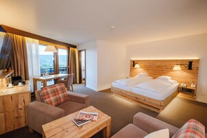 Habitación de hotel con cama de madera, un escritorio, un sofá y vistas al exterior.