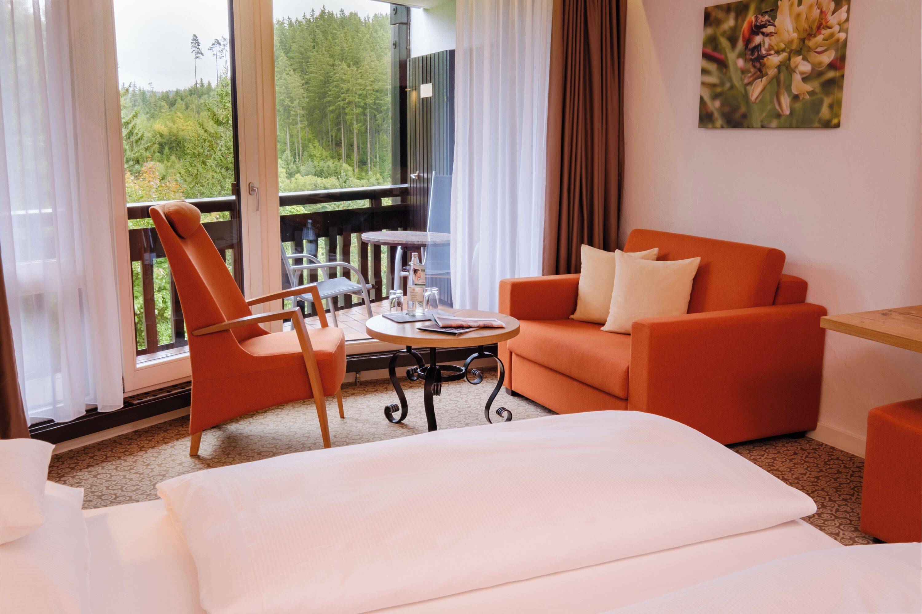 Una habitación con una cama, un sofá naranja y una mesa con una silla.