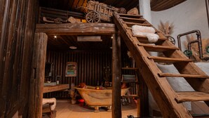 A rustic interior with a wooden ladder, a bathtub, and a wooden bench.