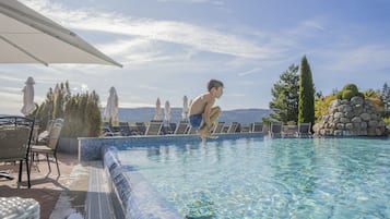 Una piscina techada, una piscina al aire libre, sombrillas