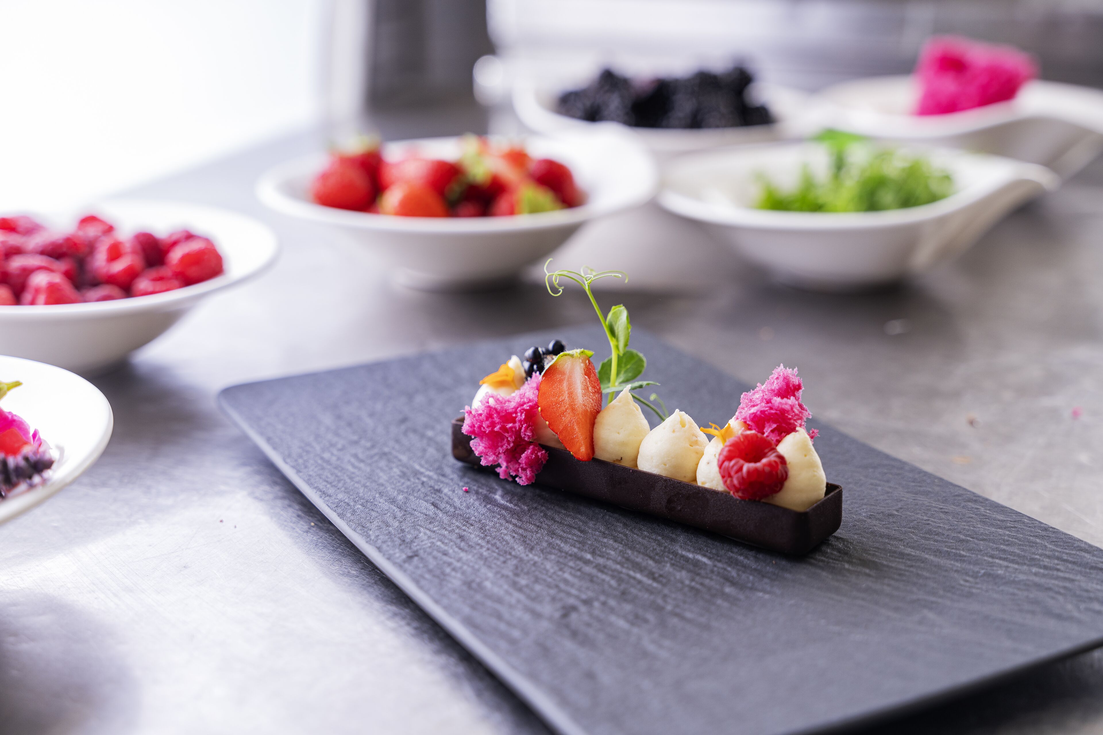 Een dessertbord met verschillende soorten fruit en een stukje chocolade op een arduinen plank.